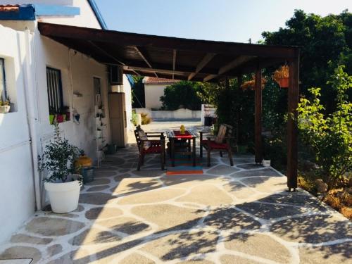 un patio con mesa y sillas bajo una pérgola en Artist Cottage in Dromolaxia, en Lárnaca