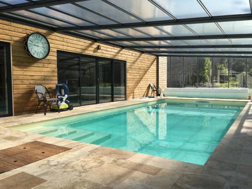 a swimming pool with a clock on the side of a house at Demeure des Pothières in Villeneuve-la-Lionne