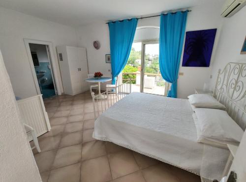 a bedroom with a bed with blue curtains and a table at Sweet Home in Ischia