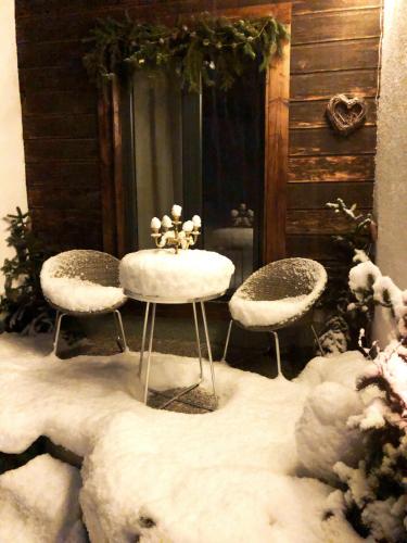 two chairs and a table in the snow at Magnifique Maison près du centre in Nendaz