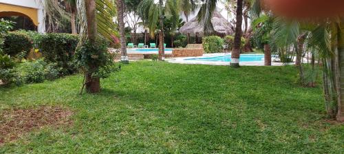 a yard with a swimming pool and palm trees at The Villa Mela, Malindi in Malindi