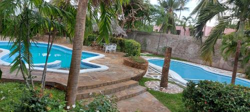 a swimming pool in a yard with palm trees at The Villa Mela, Malindi in Malindi