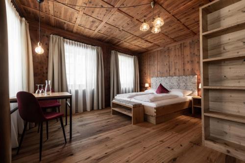 een slaapkamer met een bed, een bureau en een tafel bij Garni Hotel Tauber in Bressanone