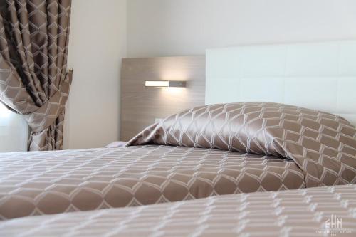 a bed with a brown comforter and pillows on it at Expo Hotel Milan in Parabiago