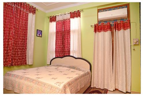 a bedroom with red and white curtains and a bed at SOHANAs Homestays- 2 BHK Luxury Apartment near Jaipur International Airport in Jaipur