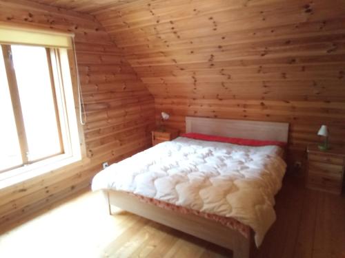 1 dormitorio con 1 cama en una cabaña de madera en Rannamaa Holiday Home, en Mändjala