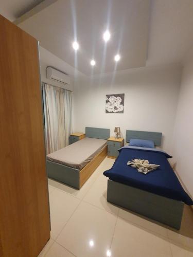 - une chambre avec 2 lits et une couverture bleue dans l'établissement Savoy, à San Pawl il-Baħar