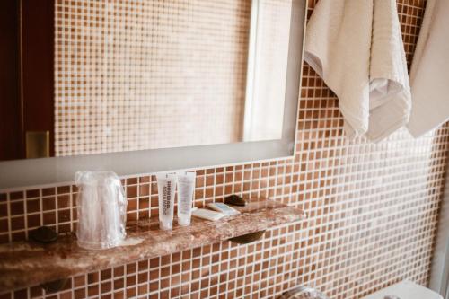 a bathroom with a mirror and a brown tiled wall at Hostal la Campana in Motril