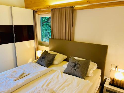 a bedroom with a bed with two pillows and a window at Alpensuite TOP 6 am Wilden Kaiser in Scheffau am Wilden Kaiser