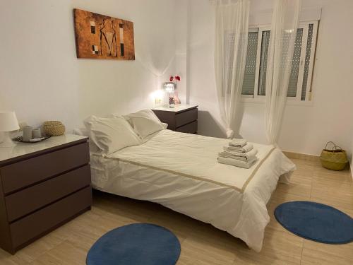 sypialnia z łóżkiem i 2 niebieskimi dywanami w obiekcie Apartamento Adimar w mieście San Luis de Sabinillas