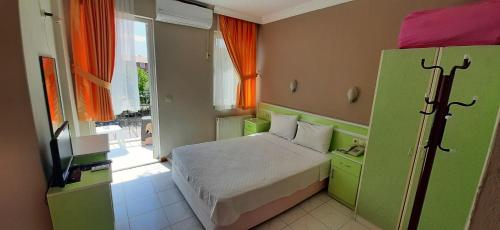 a small bedroom with a bed and a television at Tango Pension in Koycegiz