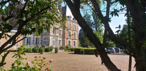 um grande edifício de tijolos com árvores em frente em Chateau de rocheux em Fréteval