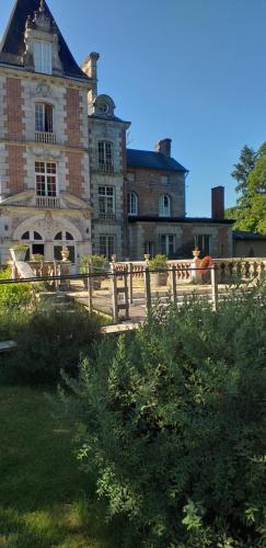 un gran edificio de ladrillo con una valla delante en Chateau de rocheux, en Fréteval