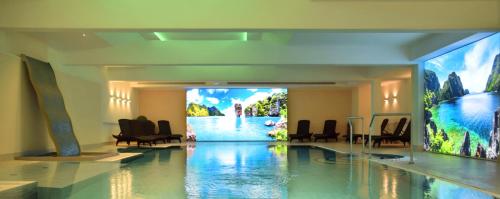 um átrio com uma piscina com cadeiras e um grande ecrã em COURT HOTEL em Halle Westfalen