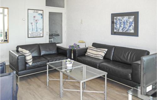 a living room with a black leather couch and a table at Zeebalkon in Bergen aan Zee