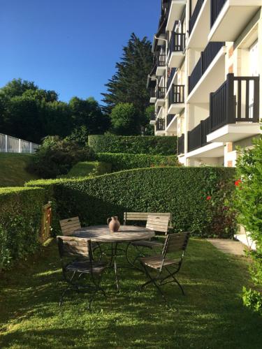 une table et des chaises dans l'herbe à côté d'un bâtiment dans l'établissement Résidence Brise du Large - Grand appartement 6 personnes magnifique vue mer, à Villers-sur-Mer