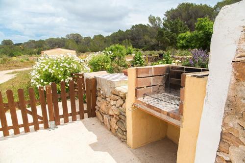 an outdoor kitchen with a stone wall and a fence at Estudio Cala Saona in Cala Saona