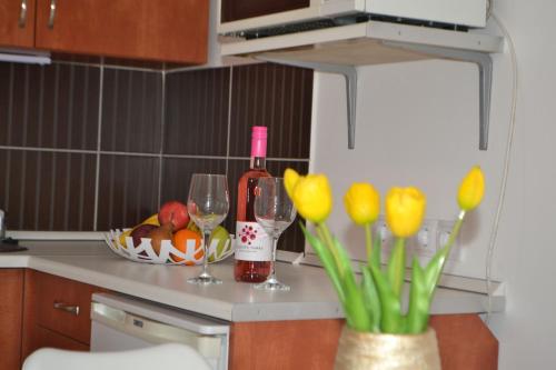 a kitchen counter with two glasses of wine and flowers at Arapartman in Zamárdi