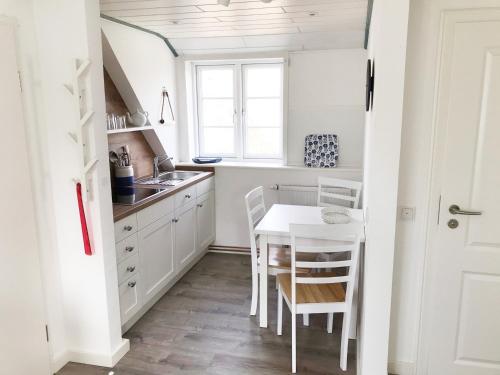 a kitchen with white cabinets and a table and chairs at Haus Frisia Ferienwohnung Frisia 4 in Norddorf