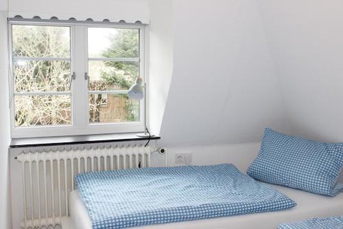 1 dormitorio con cama y ventana en Haus Frisia Ferienwohnung Frisia 5, en Norddorf