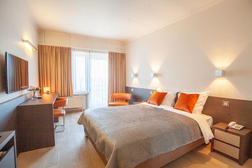 una camera d'albergo con un grande letto e una scrivania di Hotel Monaco Zeebrugge Beach a Zeebrugge