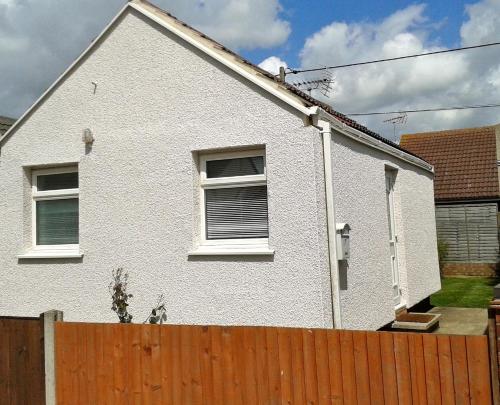 a white house with two windows and a fence at Seaside Cottage in Clacton-on-Sea