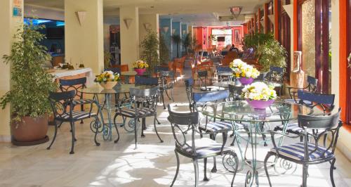 a restaurant with tables and chairs with flowers on them at Hotel Apartamentos Londres La Manga in La Manga del Mar Menor
