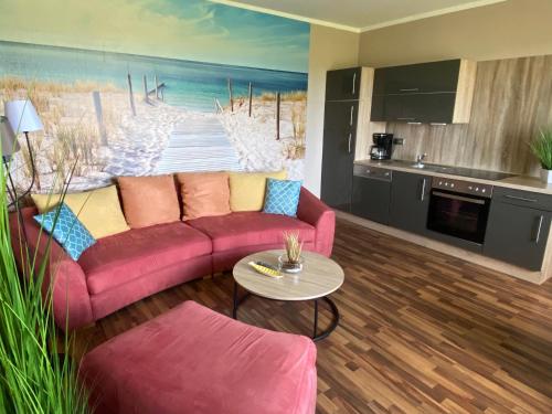 ein Wohnzimmer mit einem rosa Sofa und einer Küche in der Unterkunft Ferienwohnung PuraVida Ostsee 5A in Kühlungsborn