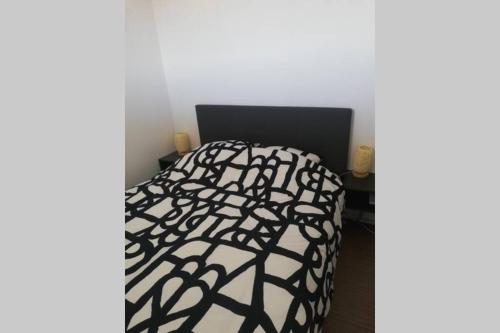 - un lit avec une couette en noir et blanc dans l'établissement Appartement T2 rénové dans résidence avec piscine, à Lacanau