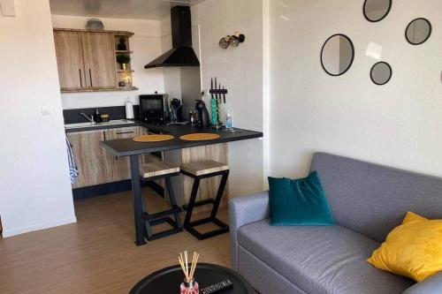 Il dispose d'une cuisine et d'un salon avec une table et un canapé. dans l'établissement Appartement T2 rénové dans résidence avec piscine, à Lacanau