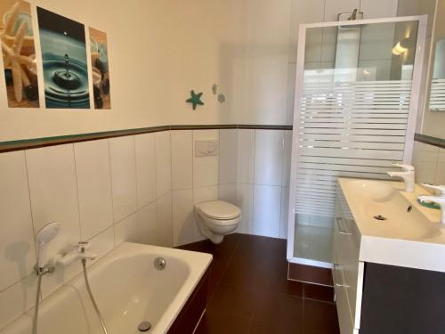 uma casa de banho com uma banheira, um WC e um lavatório. em Ferienwohnung PuraVida Ostsee 5B em Bastorf