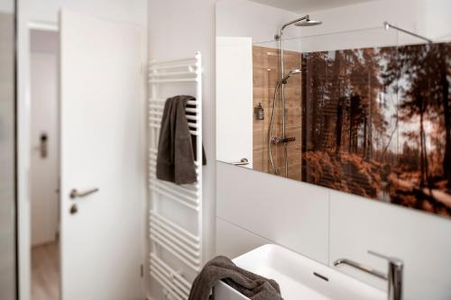 a white bathroom with a sink and a mirror at Berg und Tal Hotel & Apartments in Braunlage