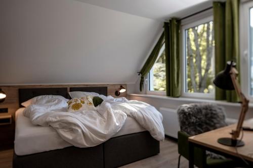 a bedroom with a bed with white sheets and a window at Berg und Tal Hotel & Apartments in Braunlage