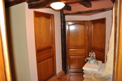 a hallway with two wooden doors and a vase of flowers at Logîte Touristique Les 3 Loups in Châtenois