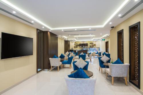 uma sala de espera com cadeiras azuis e uma televisão de ecrã plano em Myrtle Hotel - Al Sahafa em Riade
