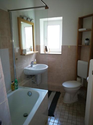 a bathroom with a tub and a toilet and a sink at Ferienwohnung Danziger OG in Celle