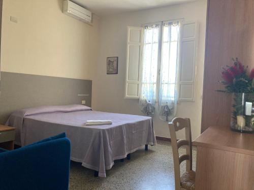 a room with a bed with a table and a window at Hotel Verdesolemare in Marina di Pietrasanta