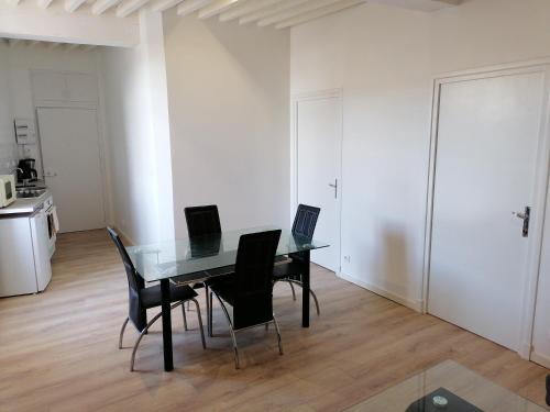 a dining room with a glass table and black chairs at Au Thiernois in Thiers