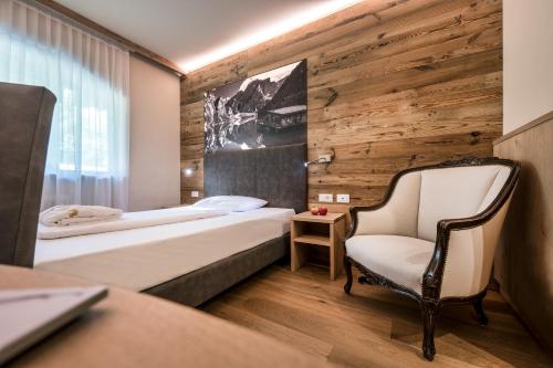 a hotel room with a bed and a chair at Parc Hotel Miramonti in Fiè