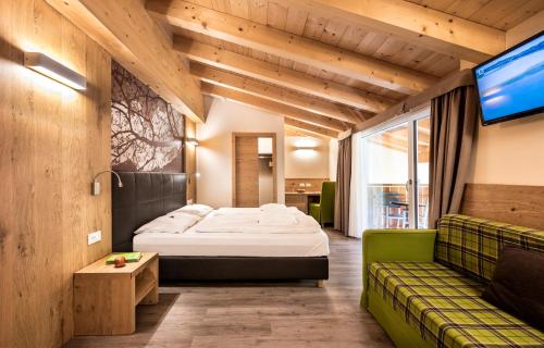 una camera d'albergo con letto e divano di Parc Hotel Miramonti a Fié allo Sciliar