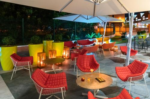 une terrasse avec des chaises rouges, des tables et un parasol dans l'établissement Savhotel, à Bologne