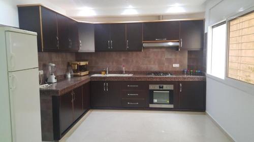 a kitchen with dark brown cabinets and a sink at La perle de saidia in Saidia 