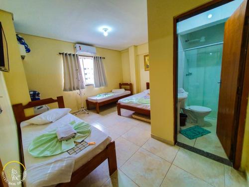 a room with two beds and a bathroom with a shower at Hotel dos Devotos in Aparecida