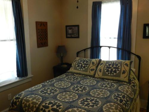 a bedroom with a bed with pillows and two windows at Helming Guest House in Hermann