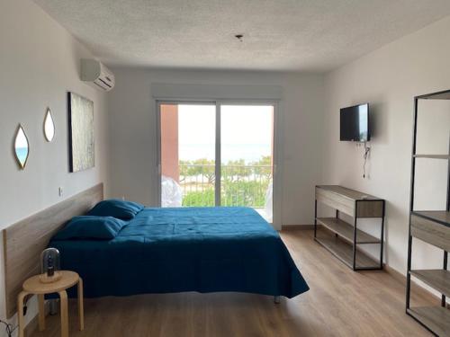 a bedroom with a blue bed and a television at Studio pieds dans l'eau in Algajola