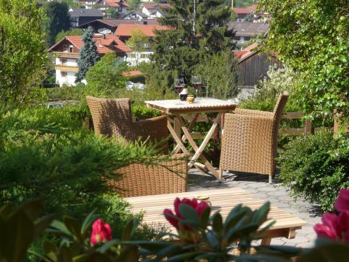 une table et des chaises en bois dans un jardin fleuri dans l'établissement Landhaus Meine Auszeit, à Bodenmais