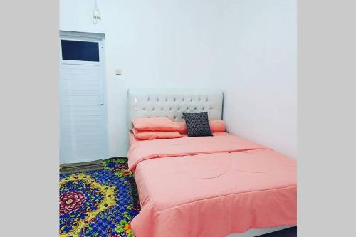 a small bedroom with a bed with pink sheets at Stay@Pitaloka in Cirebon