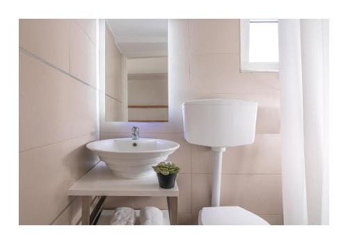 a white bathroom with a sink and a mirror at Baulus Yard Luxury I in Heraklio Town