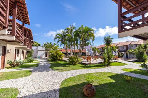 a courtyard of a house with palm trees and grass at Pousada do Timoneiro in Arraial do Cabo