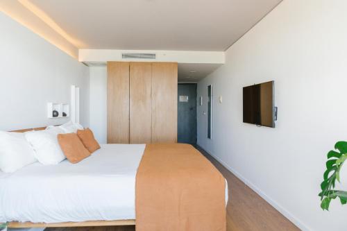 1 dormitorio con 1 cama y TV en la pared en Opta Coliving Punta Carretas, en Montevideo